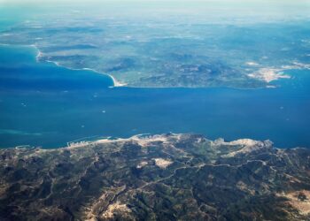Aerial view of the Strait of Gibraltar showing the narrow maritime divide between Europe and North Africa, with coastal infrastructure and shipping routes visible