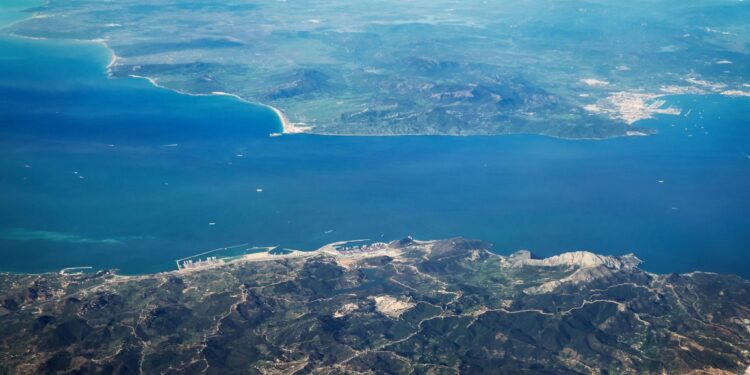 Aerial view of the Strait of Gibraltar showing the narrow maritime divide between Europe and North Africa, with coastal infrastructure and shipping routes visible