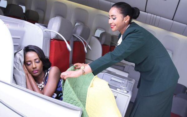 Ethiopian Airlines cabin crew assisting a passenger in business class during flight