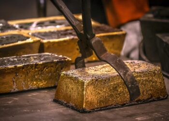 Close-up of refined gold bars being handled with industrial tongs inside a Ghanaian refinery facility