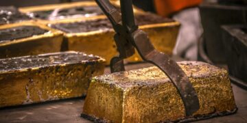 Close-up of refined gold bars being handled with industrial tongs inside a Ghanaian refinery facility