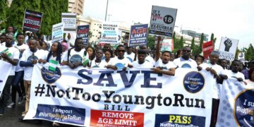 Youth protesters in Nigeria hold ‘Not Too Young To Run’ banners and placards during a political reform march calling for greater youth representation in government