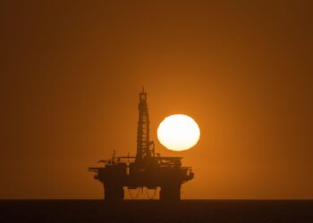 Offshore oil drilling platform silhouetted against a sunset off the coast of Namibia