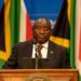 South African President Cyril Ramaphosa speaks at a podium with national flags behind him amid renewed political pressure over the Farmgate scandal