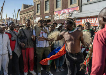 Anti-immigration protesters march through a South African township as activist Phakela Ndabandaba, wearing traditional Zulu attire, leads demonstrators carrying sticks and shields during a rally against undocumented migrants