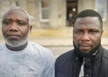 Kow Mensah (left) and Joshua Amissah (right), two Ghanaian fishermen, pose outside a court building after proceedings related to their long-running case over alleged mistreatment aboard a Scottish fishing trawler