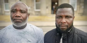 Kow Mensah (left) and Joshua Amissah (right), two Ghanaian fishermen, pose outside a court building after proceedings related to their long-running case over alleged mistreatment aboard a Scottish fishing trawler