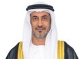 Portrait of Saeed bin Mubarak Al Hajeri, UAE Minister of State at the Ministry of Foreign Affairs, wearing a white kandura and ghutra with a black bisht trimmed in gold, facing the camera against a light grey background