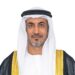 Portrait of Saeed bin Mubarak Al Hajeri, UAE Minister of State at the Ministry of Foreign Affairs, wearing a white kandura and ghutra with a black bisht trimmed in gold, facing the camera against a light grey background