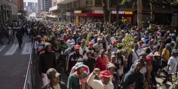 A large crowd of demonstrators marches through a city street in Johannesburg, South Africa, during a protest linked to immigration and employment concerns