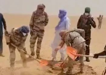 Nigerien rescue workers and security personnel dig graves in a remote Sahara desert location after recovering victims who died when a truck broke down during a journey across northern Niger