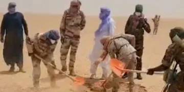 Nigerien rescue workers and security personnel dig graves in a remote Sahara desert location after recovering victims who died when a truck broke down during a journey across northern Niger
