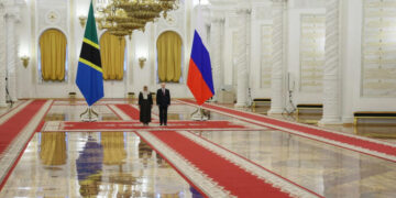 Tanzanian President Samia Suluhu Hassan stands alongside Russian President Vladimir Putin in a grand hall at the Kremlin in Moscow, with the Tanzanian and Russian national flags displayed behind them during an official state visit
