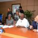 Officials from Africa Finance Corporation and Dangote Group representatives sit around a conference table during a document-signing ceremony, with media microphones in the foreground and staff observing in the background