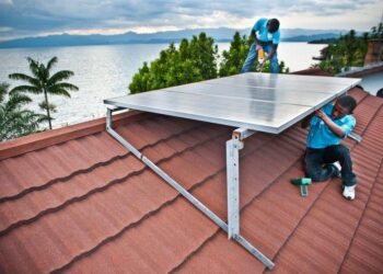 Technician installs an off-grid solar home system on a rural house in Africa, reflecting growing adoption of decentralised renewable energy solutions