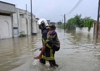 A firefighter carries a child through floodwaters in a flooded neighbourhood of Abidjan, Cote d'Ivoire, after days of heavy rainfall