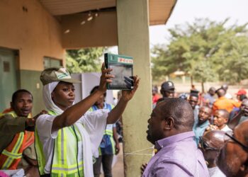 INEC official holds up a BVAS device as voters watch at an Abuja polling station