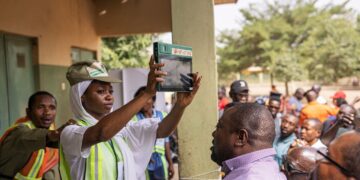INEC official holds up a BVAS device as voters watch at an Abuja polling station