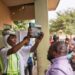 INEC official holds up a BVAS device as voters watch at an Abuja polling station