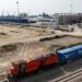 A red locomotive carries mineral freight containers through the Lobito railway terminal in Angola