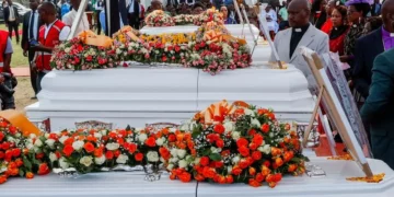 Rows of flower-covered white coffins are displayed during a memorial service for the victims of the Utumishi Girls' Academy dormitory fire in Gilgil, Kenya, as clergy, mourners and officials gather to pay their respects
