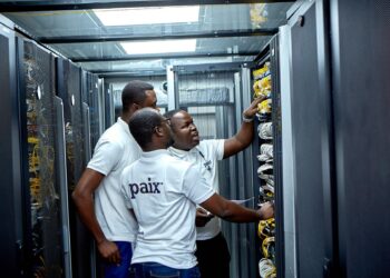 African technicians inspecting network cables and server equipment inside a PAIX data centre