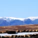 Snow-capped Maloti Mountains behind farmland and corrugated rooftops in Lesotho