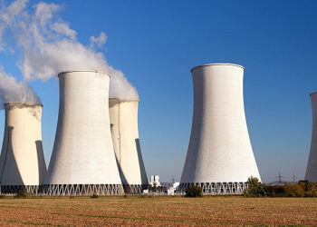 Cooling towers at a thermal power plant under a clear blue sky, representing large-scale electricity generation and energy infrastructure