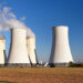 Cooling towers at a thermal power plant under a clear blue sky, representing large-scale electricity generation and energy infrastructure