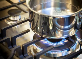 Stainless steel pot heating on a blue-flame LPG gas stove, illustrating clean cooking technology used in modern households