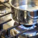 Stainless steel pot heating on a blue-flame LPG gas stove, illustrating clean cooking technology used in modern households