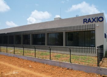 Exterior of a Raxio data centre building with secure perimeter fencing and the company’s logo displayed on the façade