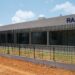 Exterior of a Raxio data centre building with secure perimeter fencing and the company’s logo displayed on the façade
